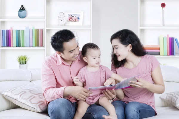 Fröhliche Familie mit Buch im Wohnzimmer — Stockfoto