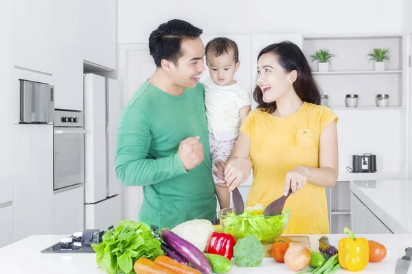 Vidám szülők és a gyermek, hogy saláta — Stock Fotó