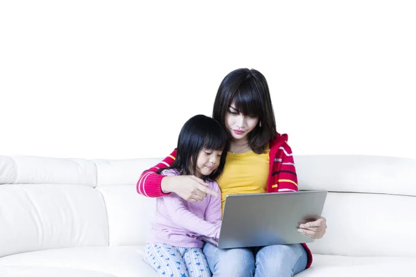 Menina e mãe usam laptop no sofá — Fotografia de Stock