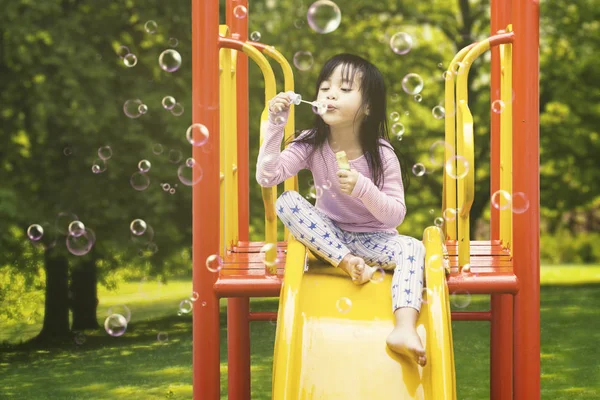 Mädchen pustet Seifenblasen auf Rutsche — Stockfoto