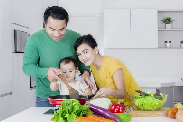 Маленькая девочка готовит с родителями на кухне — стоковое фото
