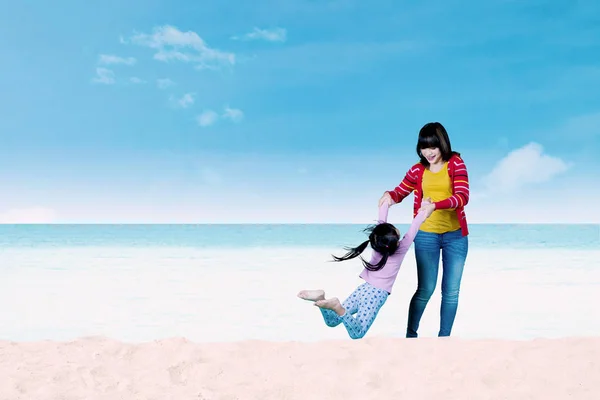 Madre oscillando il suo bambino sulla spiaggia — Foto Stock