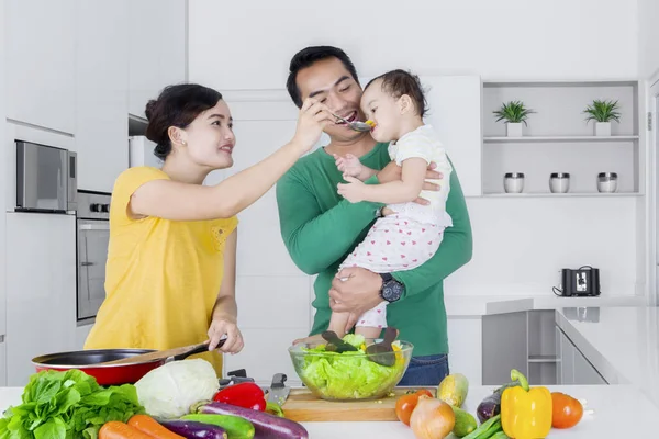 Eltern füttern kleines Mädchen in Küche — Stockfoto