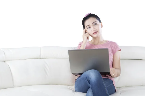 Pensive woman uses laptop on couch — Stock Photo, Image