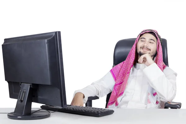 Smiling arabian man looking at monitor — Stock Photo, Image