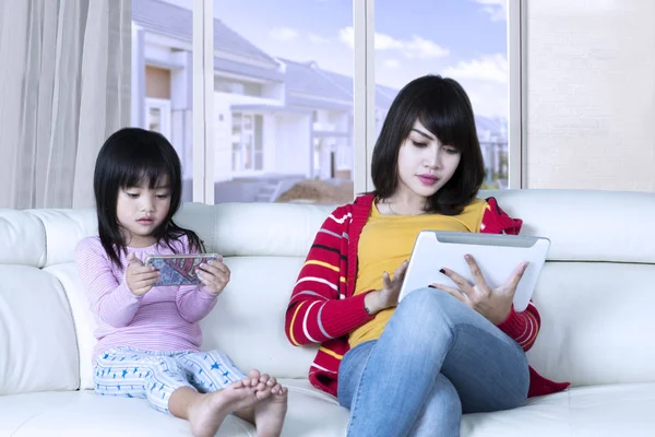 Mulher e criança parece ocupado com gadgets — Fotografia de Stock