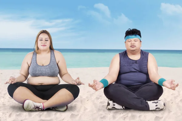 Vrouw en vriend doet yoga op het strand — Stockfoto
