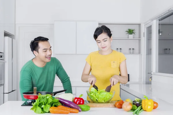 Jovem esposa fazendo salada com o marido — Fotografia de Stock