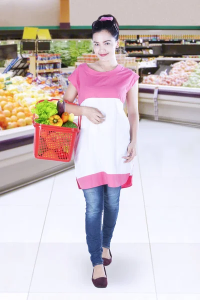 Mujer joven comprando verduras en la tienda de comestibles — Foto de Stock