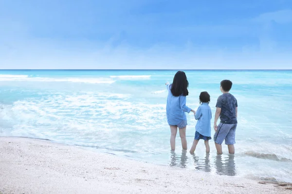 Frau und Kinder stehen an der Küste — Stockfoto