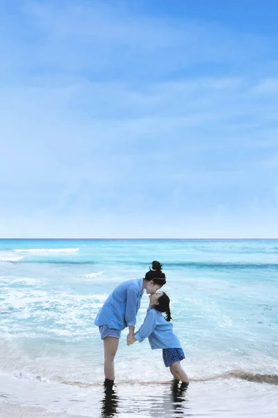 Madre besando a su hija en la costa — Foto de Stock