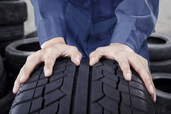 Mãos mecânicas empurrando pneu — Fotografia de Stock
