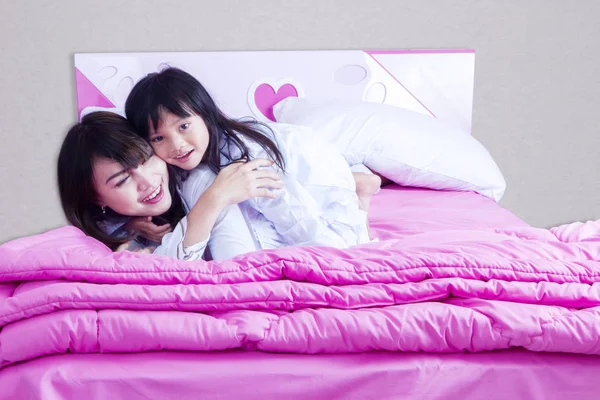 Счастливая мать и ребенок лежат на кровати — стоковое фото