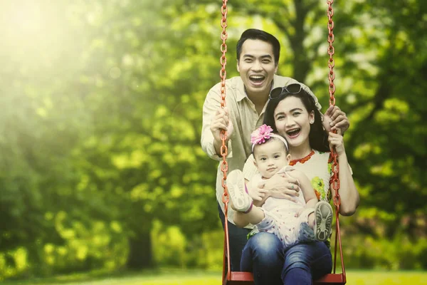 Familia feliz jugando swing en el parque — Foto de Stock