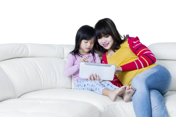 Девочка и мама с планшетом отдыхают на диване — стоковое фото