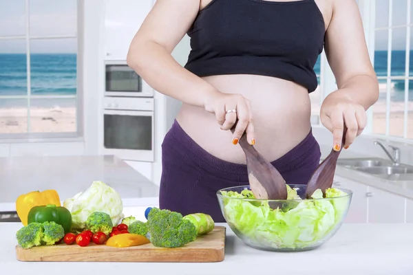Madre embarazada hace ensalada con un tazón —  Fotos de Stock
