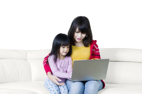 Linda chica y madre usando el ordenador portátil en el sofá —  Fotos de Stock