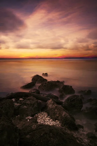 Farbenfroher Sonnenuntergang mit Felsen am Strand — Stockfoto
