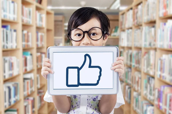 Child shows OK sign on tablet in library — Stock Photo, Image