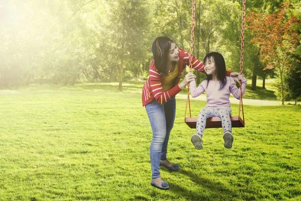 Ребёнок и мать играют на качелях — стоковое фото