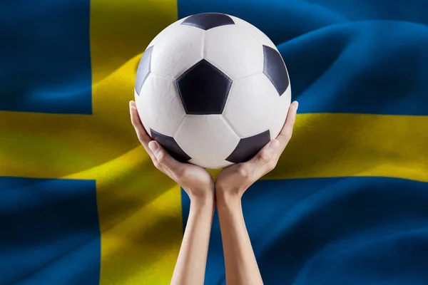 Руки, що тримає м'яч з прапор Швеції — стокове фото