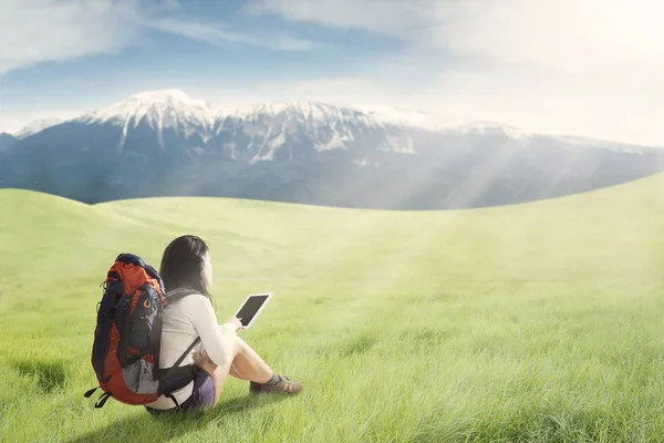 Female hiker with digital tablet on meadow — Stock Photo, Image