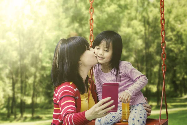 Madre bacio sua figlia su un altalena — Foto Stock