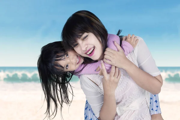여자와 아이 피기백 타고 해변에서 — 스톡 사진