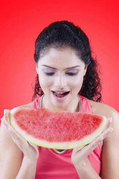 Mulher comendo melancia doce no fundo vermelho — Fotografia de Stock