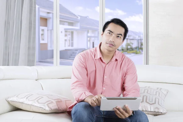 Junger asiatischer Mann benutzt Tablette auf Couch — Stockfoto