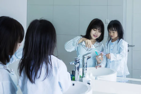 Young mother and daughter brush teeth — Stock Photo, Image