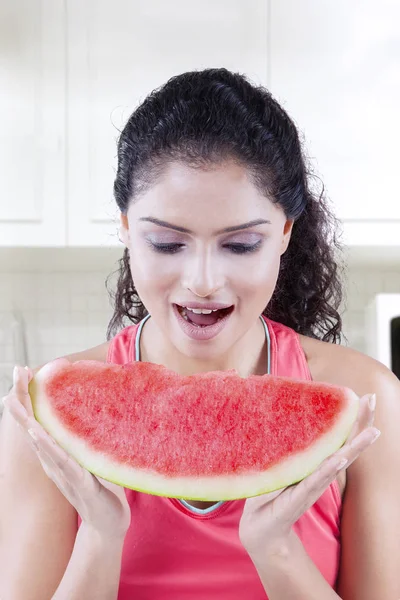 Jovem mulher comendo melancia na cozinha — Fotografia de Stock