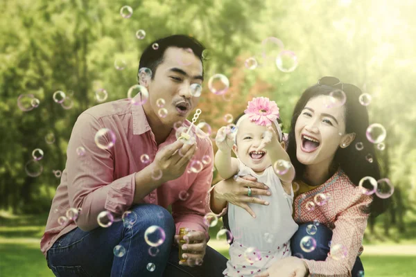 在公园里吹泡泡的亚洲家庭 — 图库照片