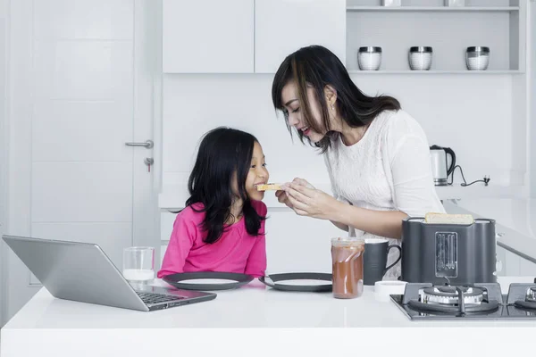Красива донька годує матір на кухні — стокове фото