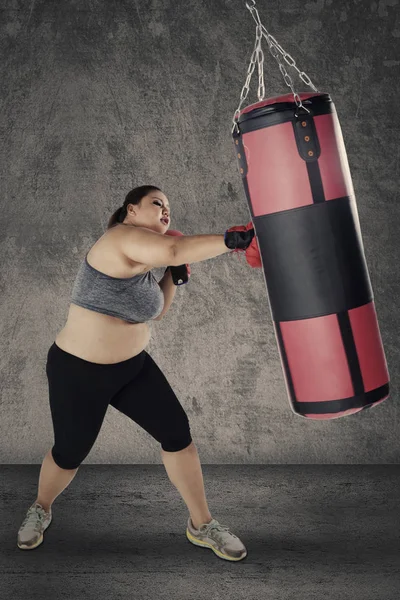 Mulher loira batendo um saco de boxe — Fotografia de Stock