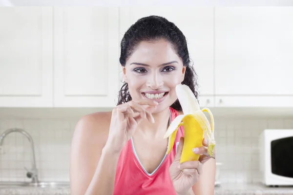 Ajuste mujer pelando un plátano en la cocina —  Fotos de Stock