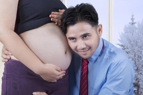 Šťastný otec poslouchá těhotné bříško — Stock fotografie