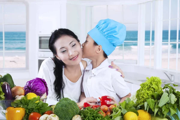 Kid beija sua mãe enquanto cozinha — Fotografia de Stock