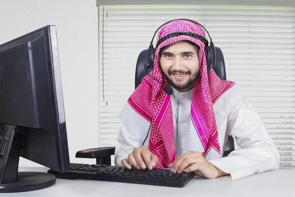 Muslim operator working with computer and headphone — Stock Photo, Image