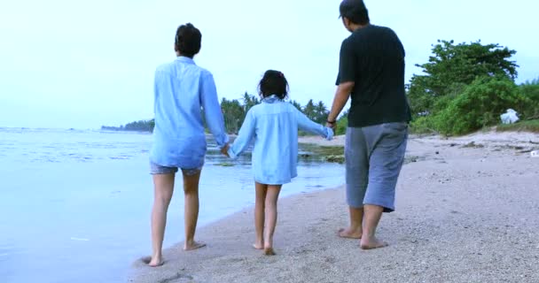 Barn och hennes föräldrar promenad på stranden — Stockvideo