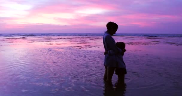 Silueta mujer y niño de pie en la playa — Vídeos de Stock