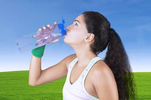 Indian woman drinks water in meadow