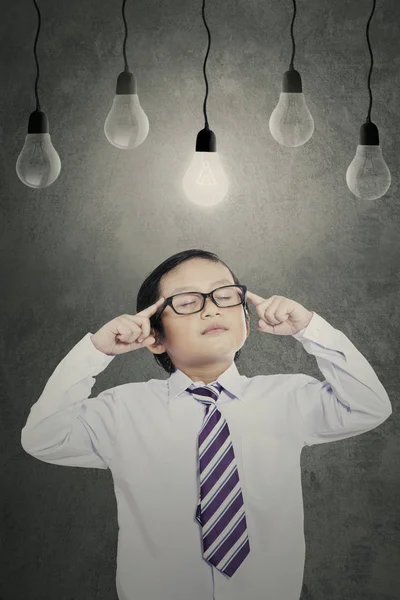 Liten pojke med glödlampor i klassrummet — Stockfoto