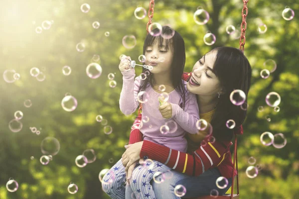 Meisje met moeder spelen zeepbellen — Stockfoto