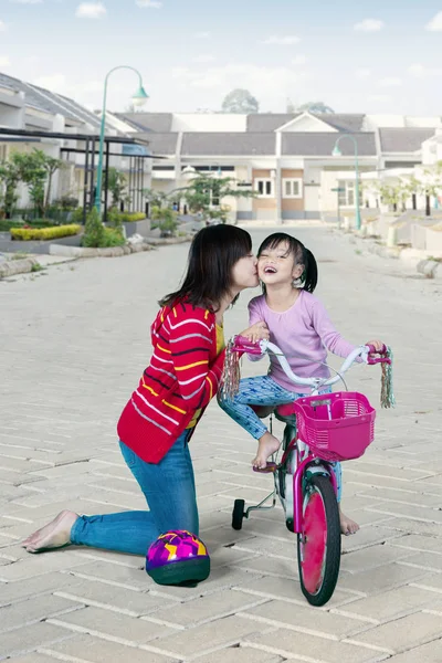 Mãe beijando sua filha em uma bicicleta — Fotografia de Stock