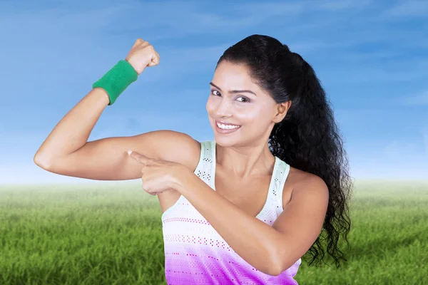 Mujer joven mostrando su bíceps en el prado — Foto de Stock