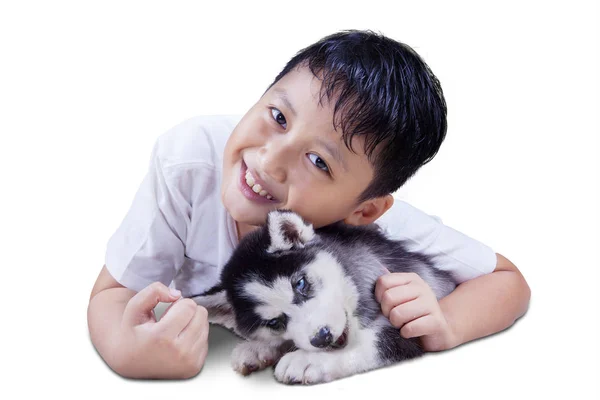 Allegro ragazzo abbracciando husky cucciolo su studio — Foto Stock