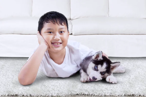 Bonito menino brinca com cachorro husky em casa — Fotografia de Stock