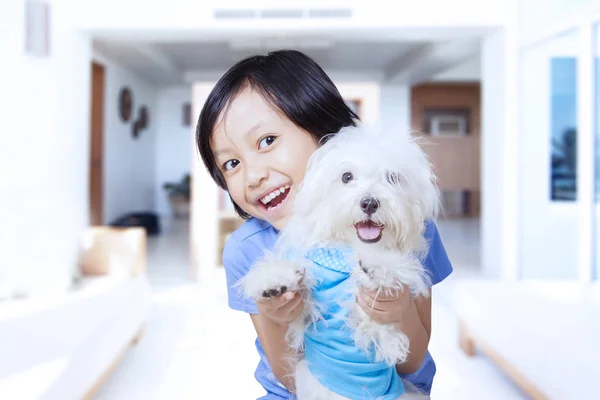 Linda chica abrazando a su cachorro en casa —  Fotos de Stock