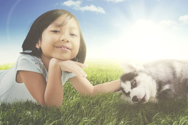 Niña acostada con un cachorro en el prado —  Fotos de Stock